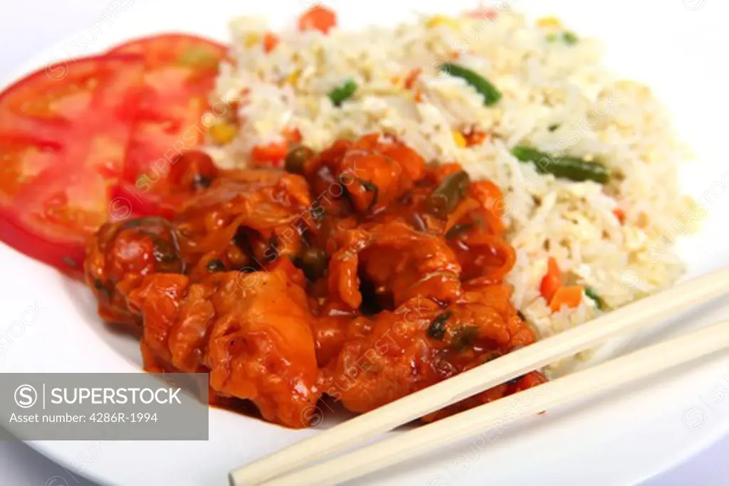 Chicken sweet and sour with vegetable fried rice on a plate with chopsticks