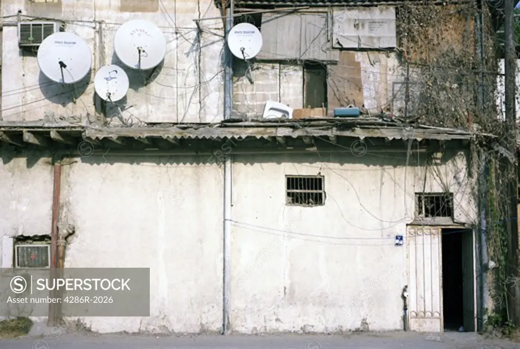 A slum dwelling in the backstreets of central Doha, November 2009, adorned with four satellite dishes. TV provides a vital link with home for the impoverished Asian labourers.