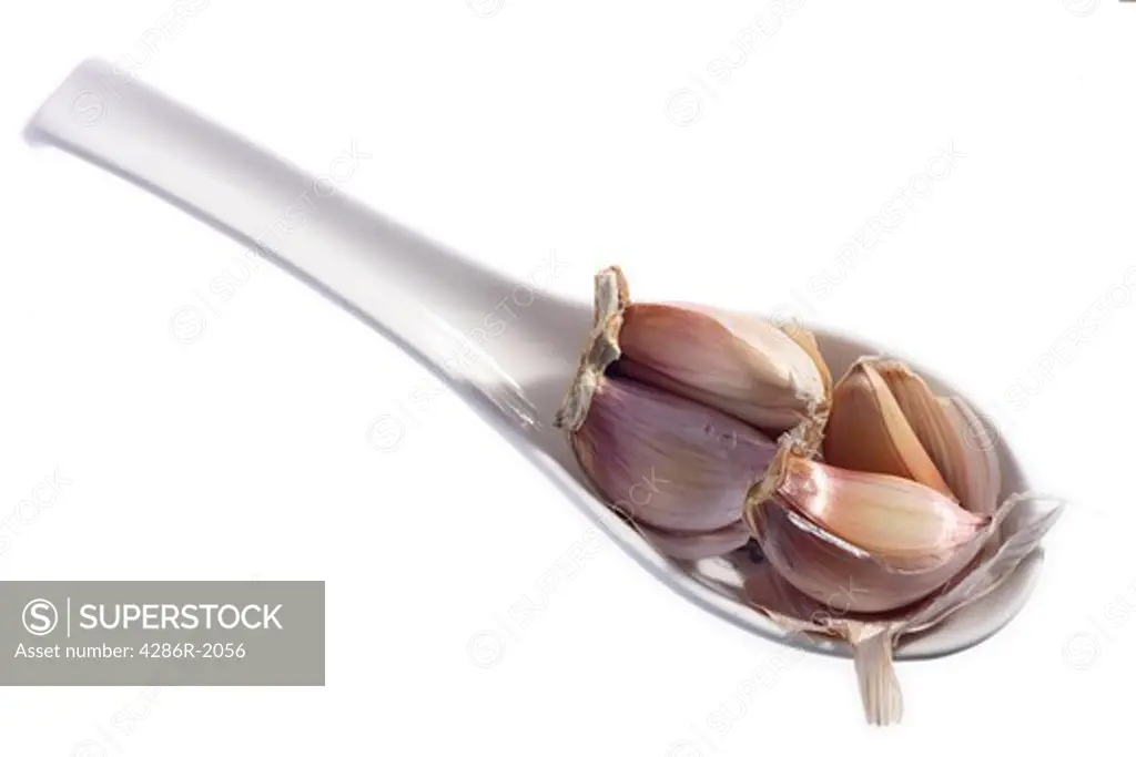 Cloves of garlic on a spoon, one of a series of spices all shot in the same way.