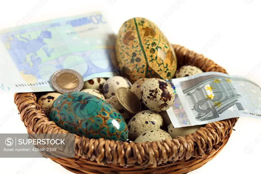 A basket full of different quails and artificial eggs together with euro currency notes and coins. A financial or business concept representing a nest egg or everything being in a single basket