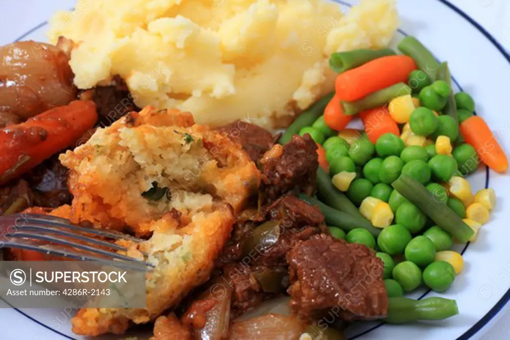 A traditional English parsley dumpling with beef stew, potatoes and mixed vegetables