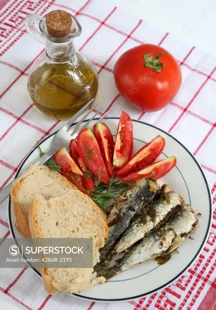A healthy meal of baked sardines (pilchards) with bread, tomatoes and olive oil, high in Omega-3 oils, Vitamin D and polyunsaturates
