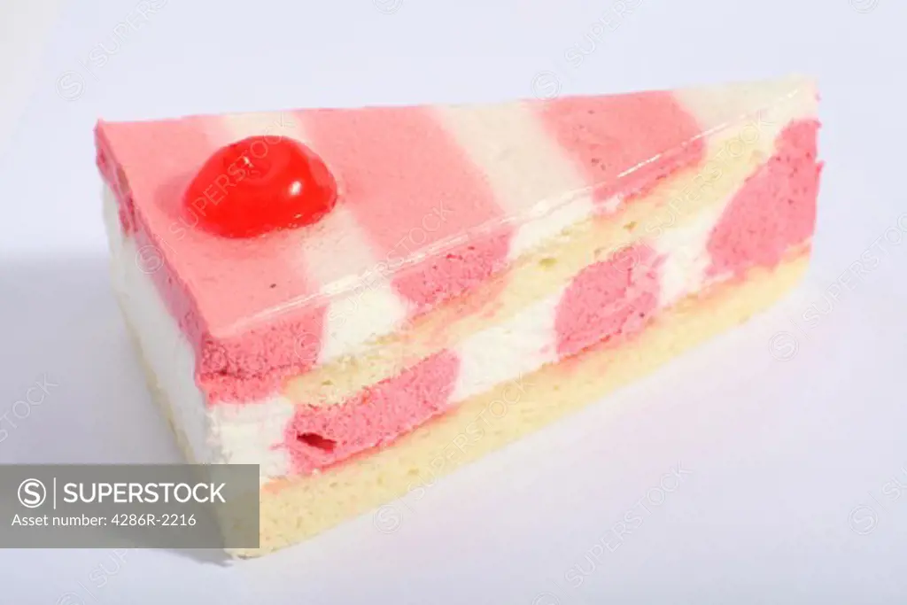 A slice of strawberry and vanilla sponge cake with icing, a cherry and a gelatin topping