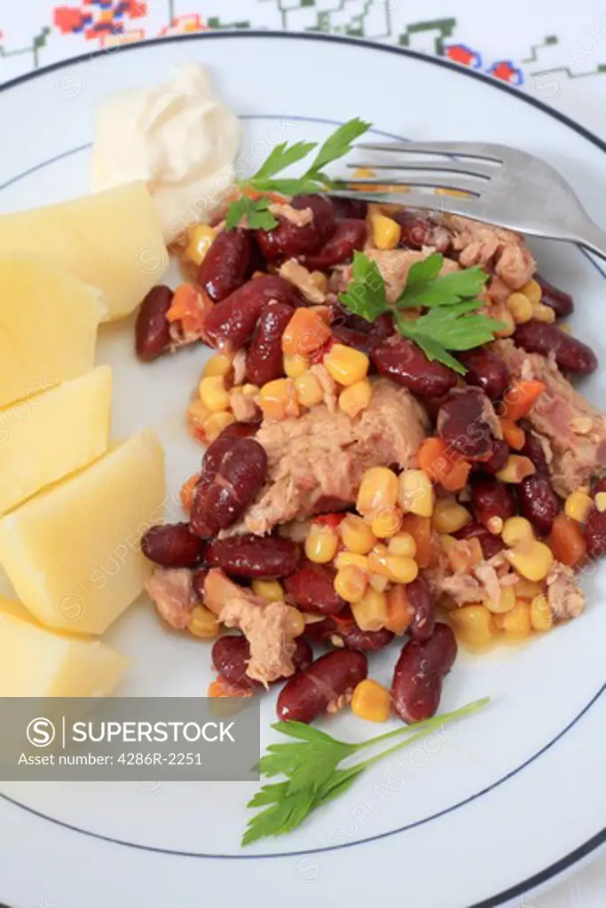 A healthy meal of tuna, bean and sweetcorn salad, with boiled potatoes and mayonnaise, vertical