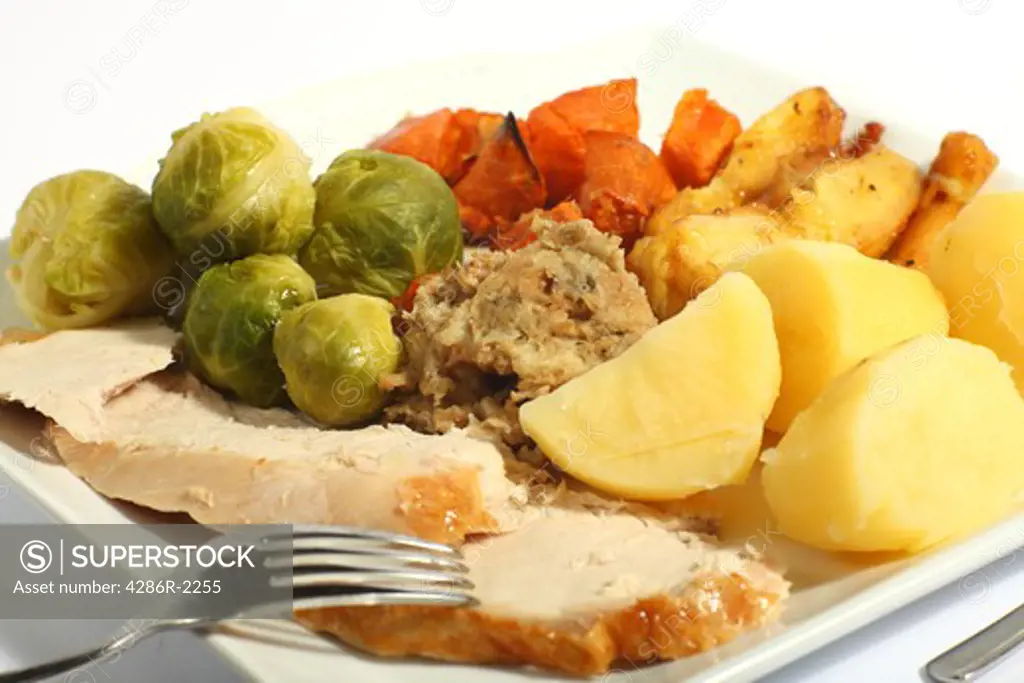 A meal of roast turkey with all the trimmings - brussels sprouts, roast sweet potatoes, roast parsnips stuffing and boiled potatoes