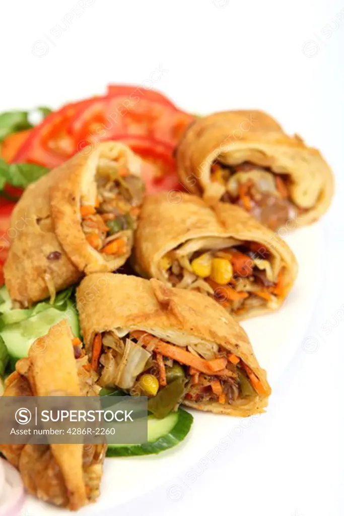Chinese-style vegetable spring roll wraps, served on a plate with a salad