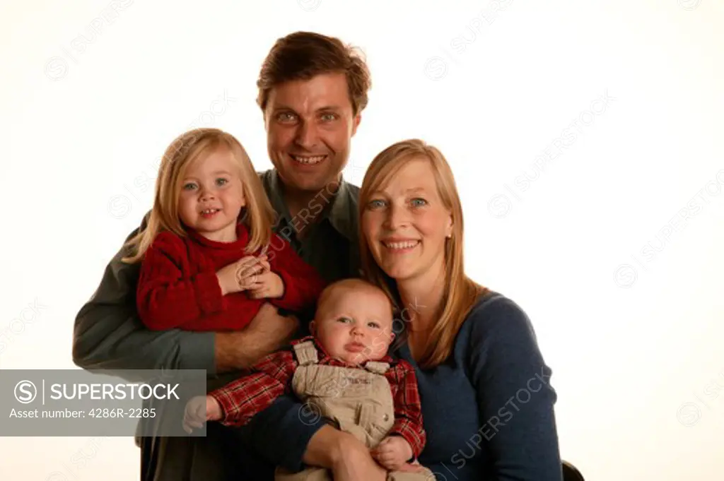 Studio shot of a mother and a father holding their young daughter and baby.