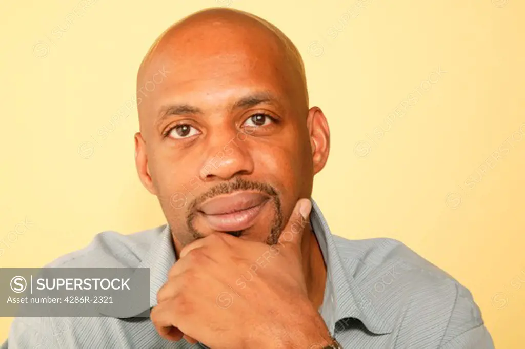 Studio shot of an African-American man with his chin in his hand looking serious.