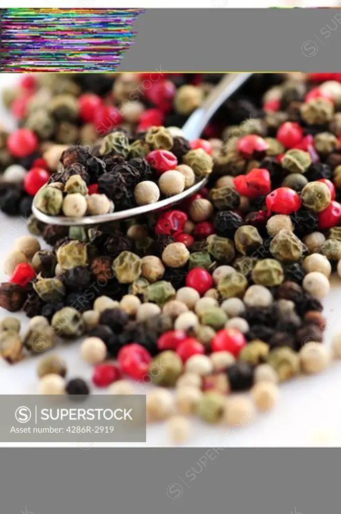 Mixed assorted peppercorns on white background macro