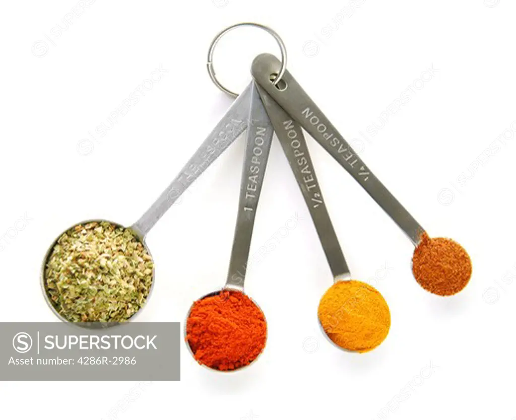 Assorted spices in measuring spoons on white background