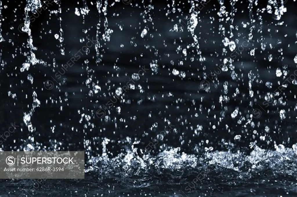 Falling water drops on dark background close up