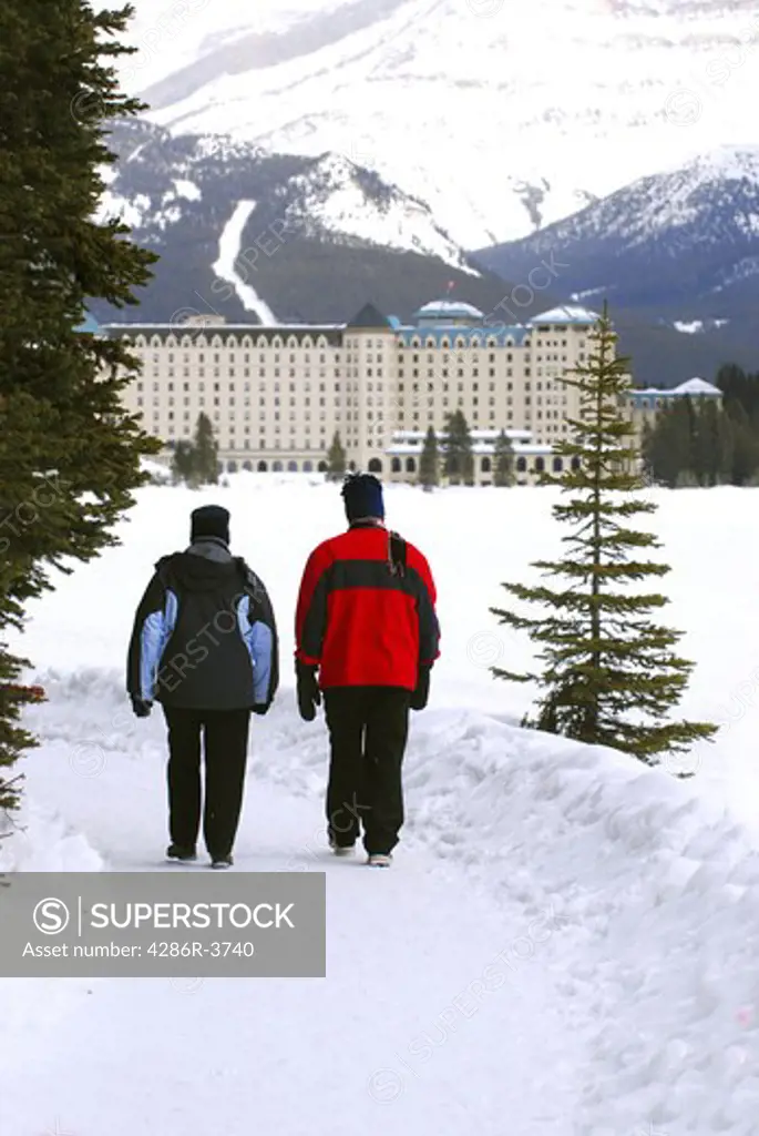 A couple talking a walk in on scenic winter path at Chateau Lake Louise