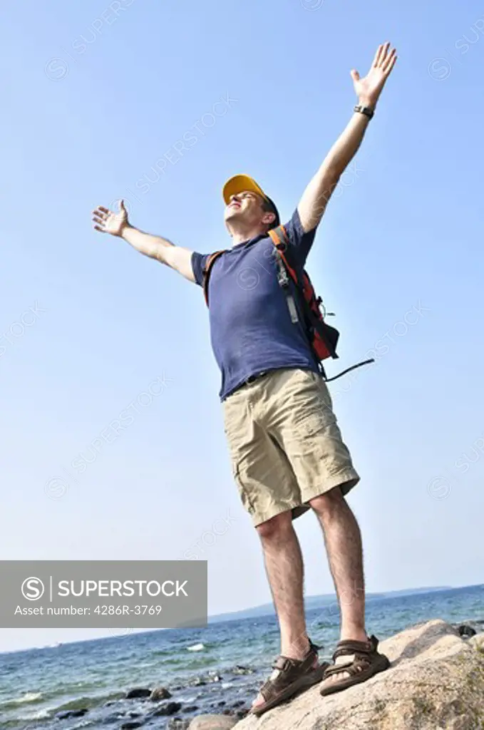 Middle aged hiker standing on top of a mountain raising his arms