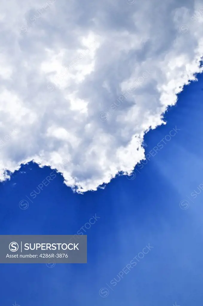 Blue sky with sunrays shining from behind the clouds