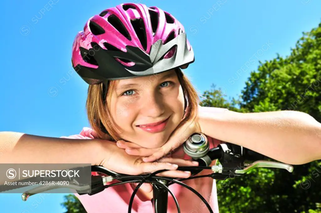 Portrait of a teenage girl on a bicycle in summer park outdoors