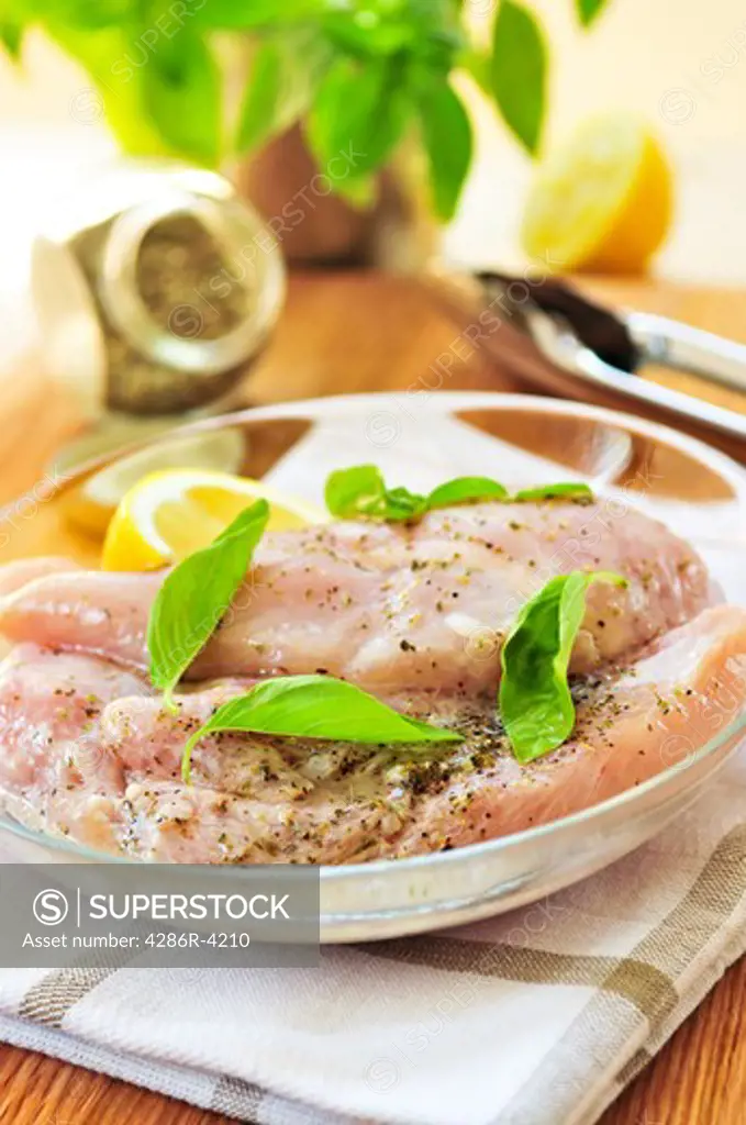 Marinating raw chicken breasts in lemon juice and herbs
