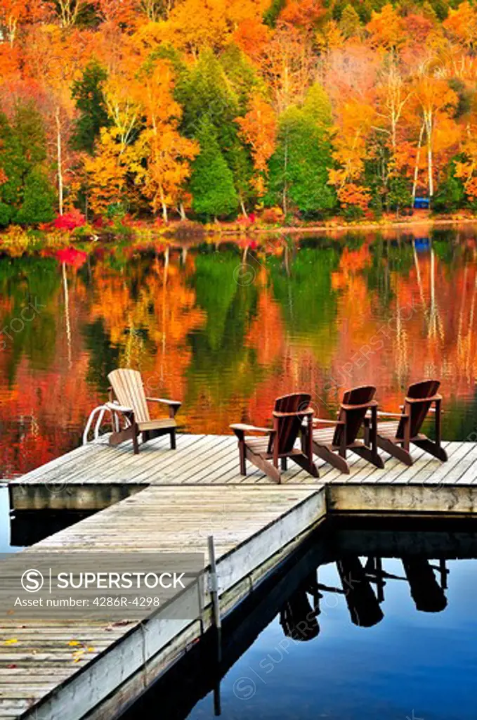 Wooden dock with chairs on calm fall lake