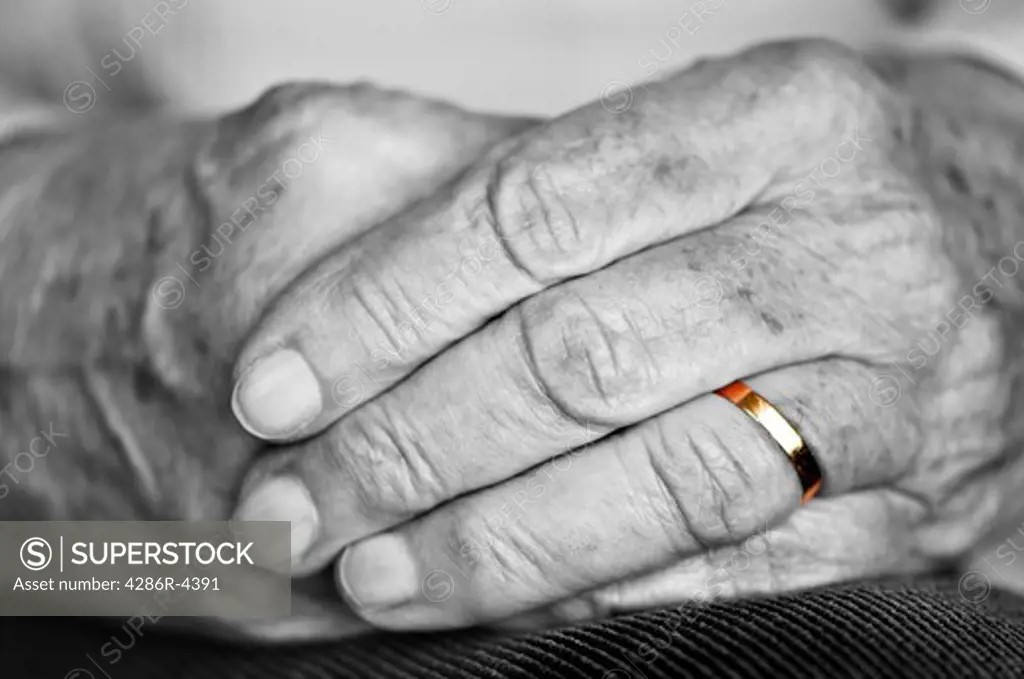 Close up on elderly woman hands with golden wedding ring