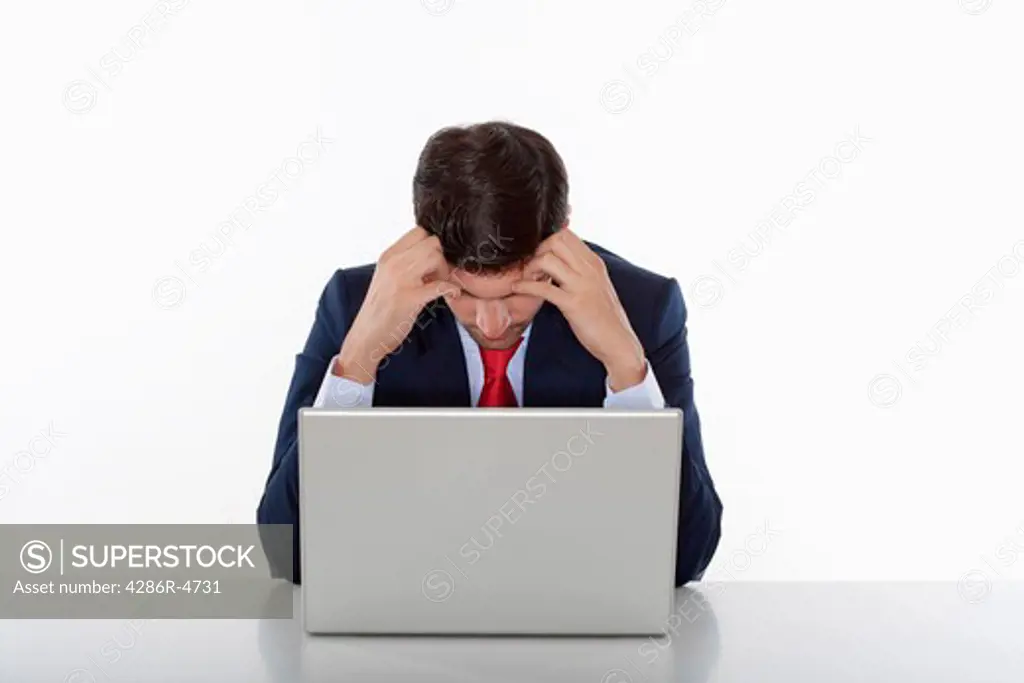 worried business executive in suit behind desk with laptop