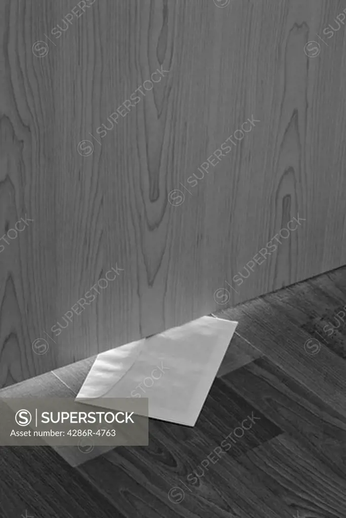 white envelope with message slipped under wooden door