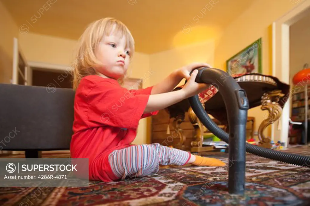boy with long blond hair helping with vacuum cleaning