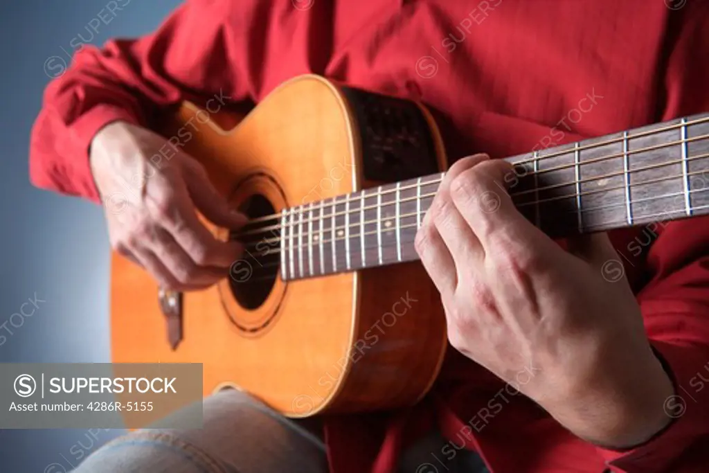 closeup of hands of a musician playing acoustic guitar