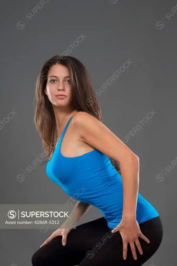 energetic young woman with blue top dancing - isolated on gray background