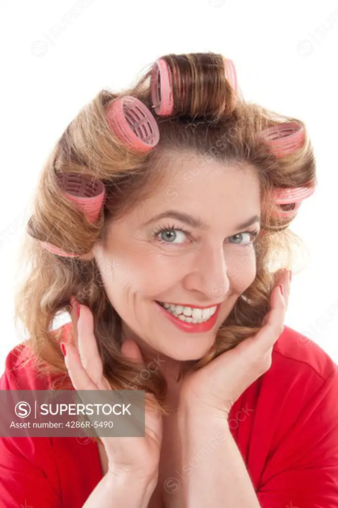 happy middle-aged woman in red with hair rollers - isolated on white