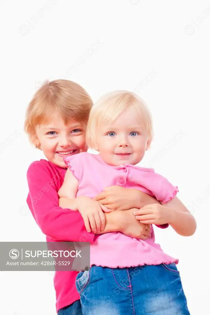 two sisters - older sister carrying the younger one, laughing - isolated on white