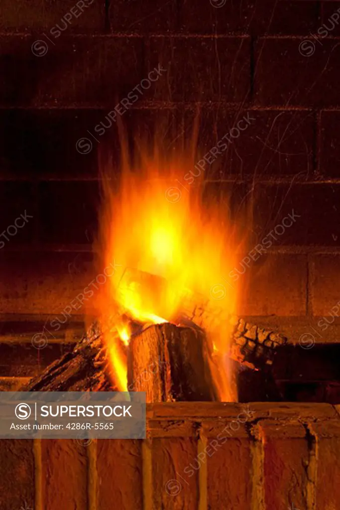 brick fireplace with large pieces of wood burning giving warmth