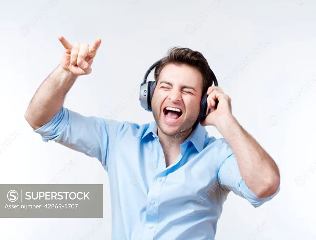 man in blue shirt with earphones listening to music - isolated on gray