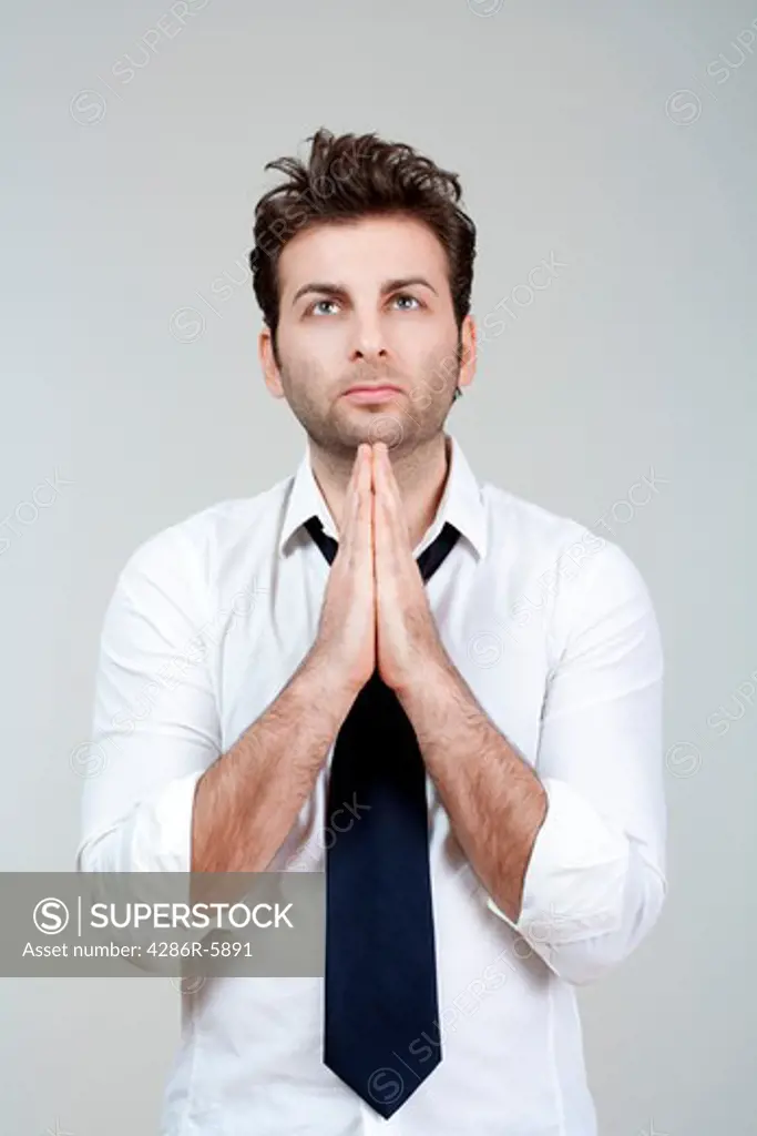 businessman in white shirt and tie holding hands together, praying - isolated on gray