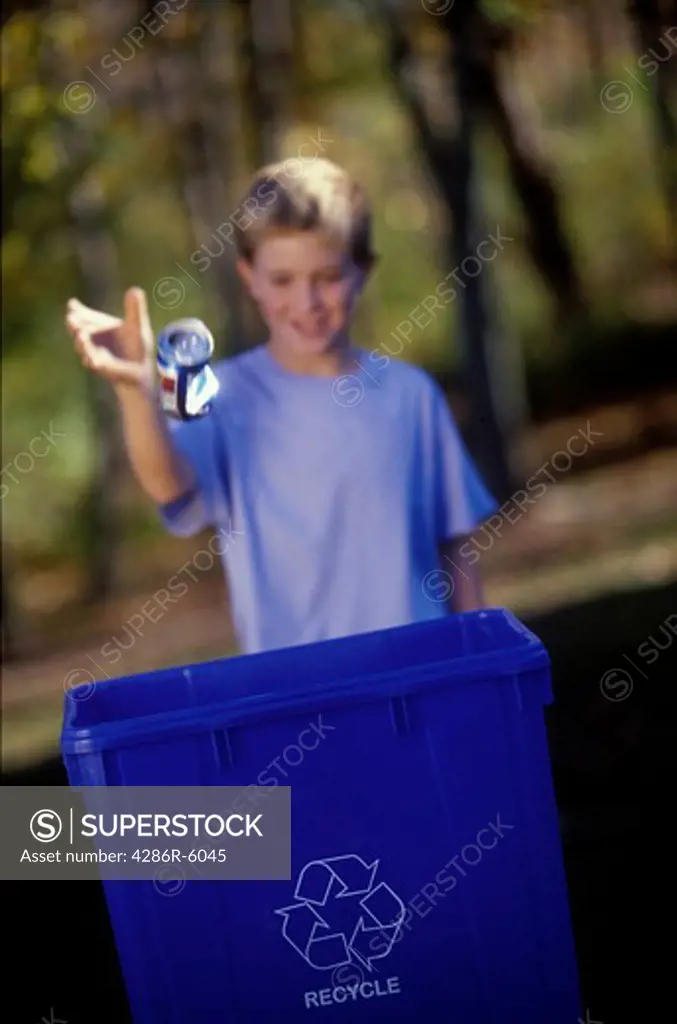 Young caucasian male child throwing can into a recycle bin