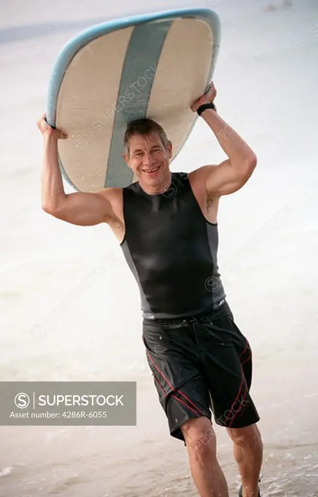 Male surfer coming out of the ocean carrying his surfboard