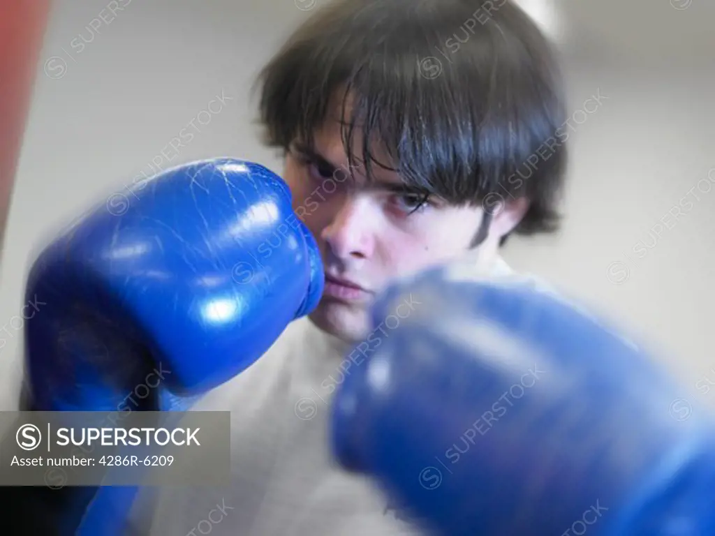Young caucasian male wearing boxing gloves looking intent