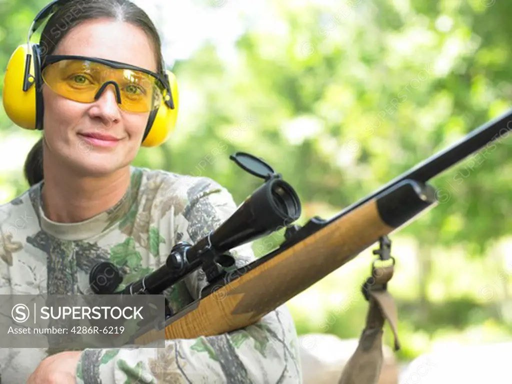 Medium close up portrait of woman holding a hunting rifle