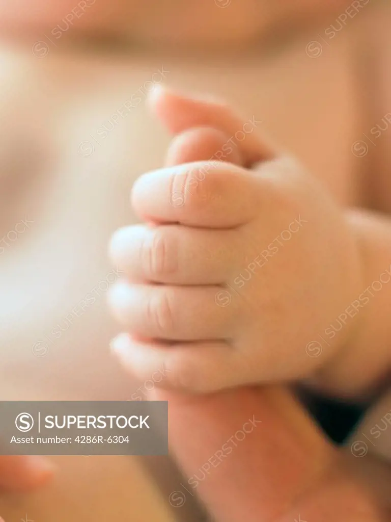 Extreme close up of an infants hand grasping the finger of an adult.