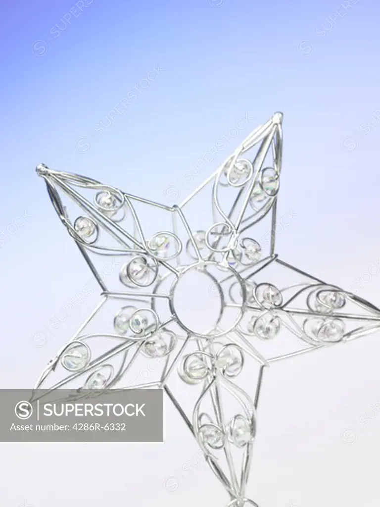 Vertical studio image of a metallic christmas star on a blue background.