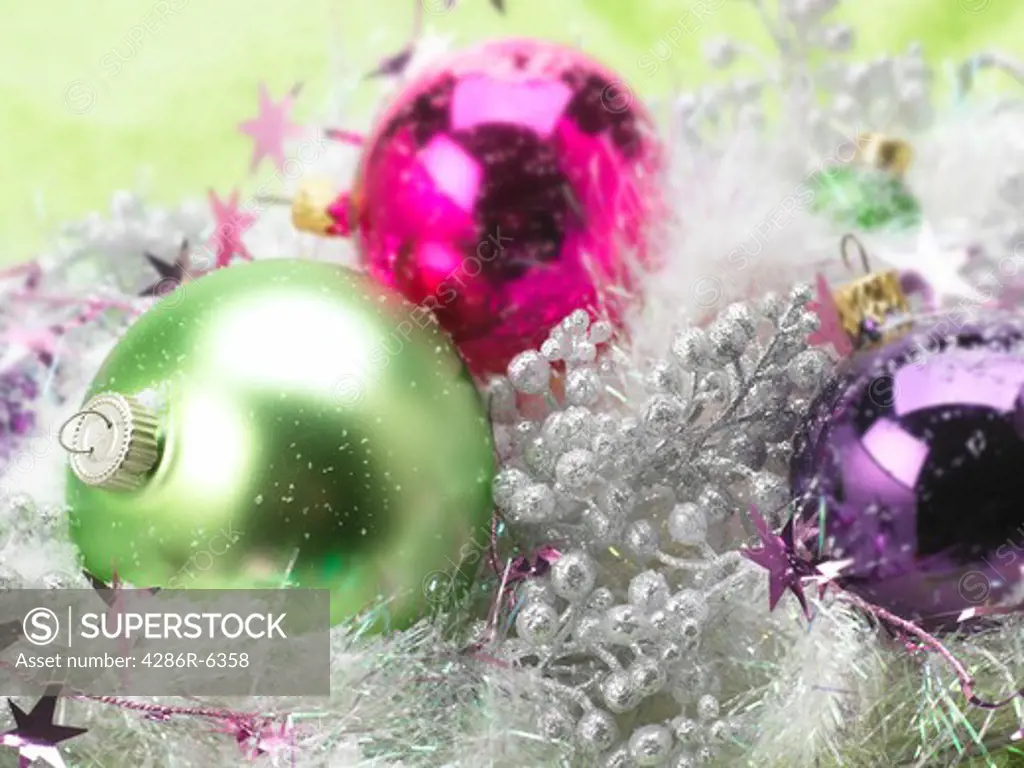 Horizontal close up of hot pink, green and purple tree ornaments with silver accents