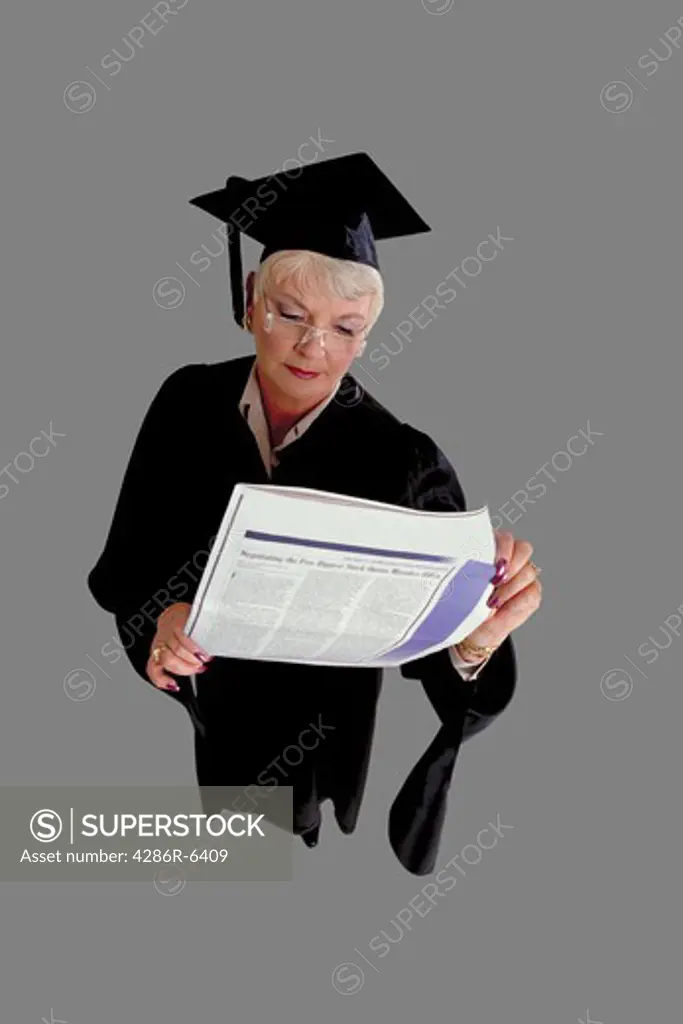 Birdseye view of older woman in cap and gown reading want ads in newspaper