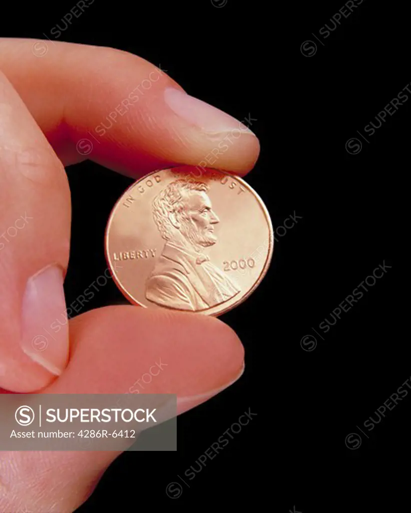 Close up of fingers holding a penny
