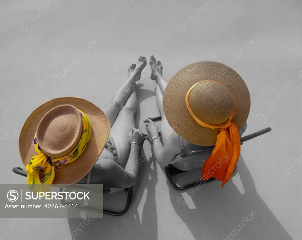 Birdseye view of two women sitting at pool in sun hats