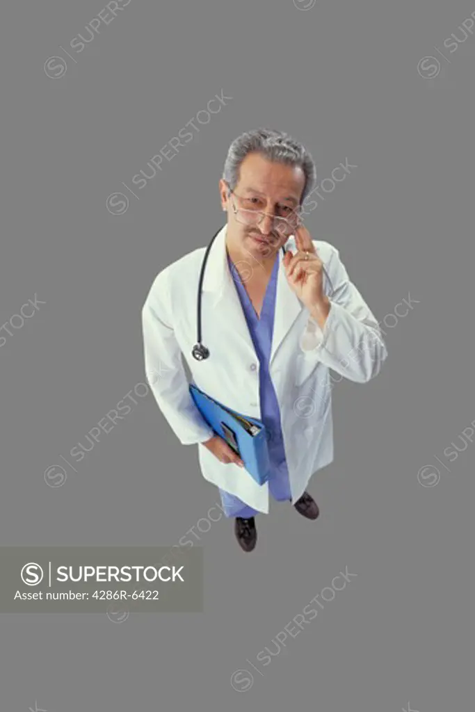 Birdseye view of a doctor in lab coat holding patient file and looking thoughtfully at camera
