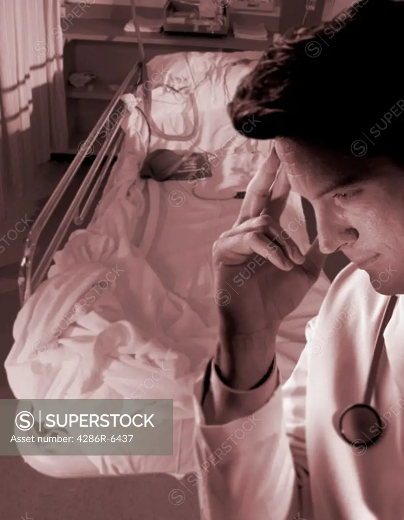 Medium close up of a doctor with a worried expresson standing in front of empty hospital bed