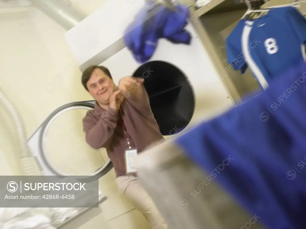 Portrait of a down syndrome male at work tossing laundry into a hamper