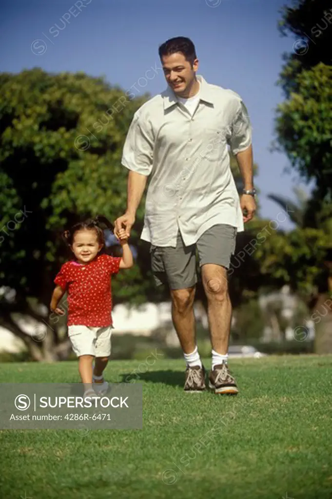 Hispanic father holding his daughters hand while walking