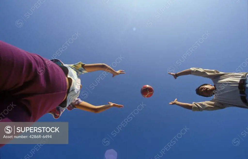 Unusual angle of adult and child playing catch with a volley ball