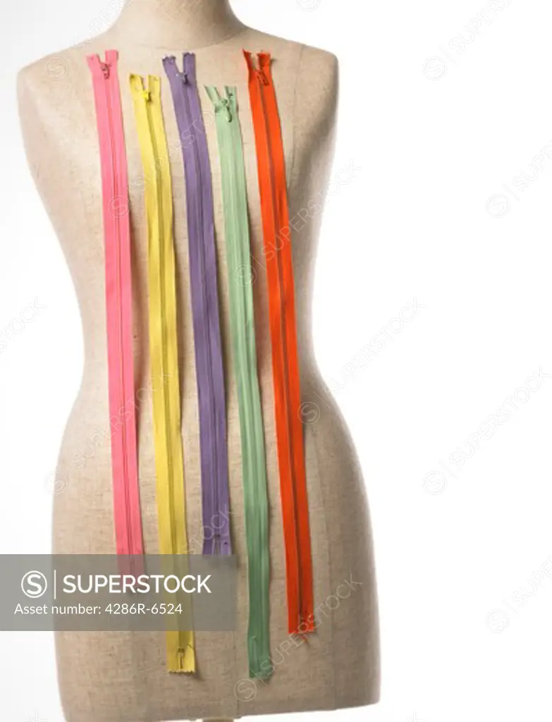 Pastel colored zippers pinned across the chest of a dressmakers form.