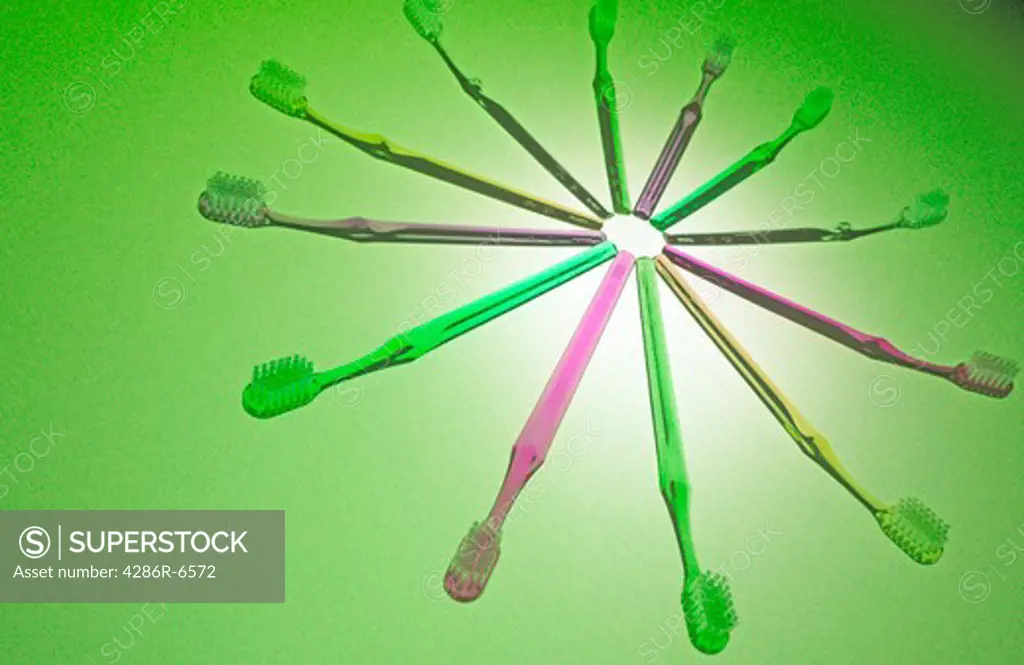 Still life of olorful tooth brushes laid out on green seamless.