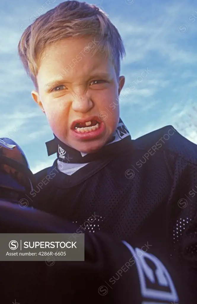 Medium close up of a young boy with only one top tooth making a scary face.